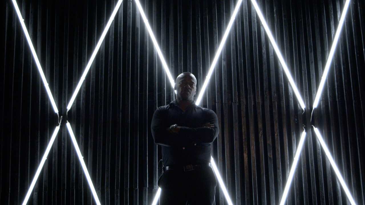 a man with crossed arms in front of white lights